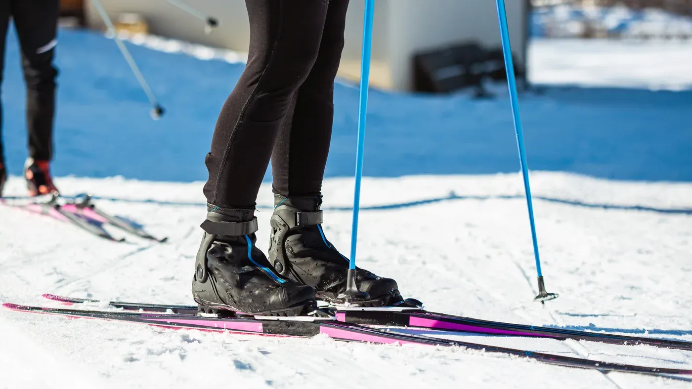 Längdskidåkare står på skidorna i snön med stavarna bredvid