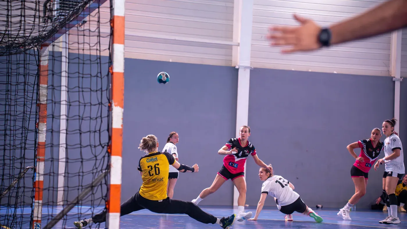 Målvakt gör en split för att rädda ett skott under en damhandbollsmatch inomhus