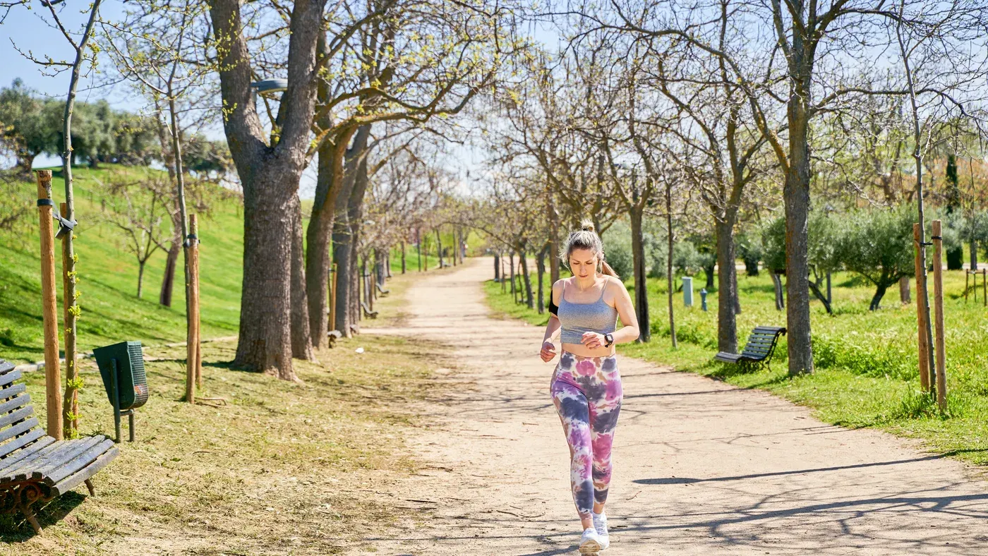 Nybörjarlöpare joggar lugnt längs en grusväg i parken
