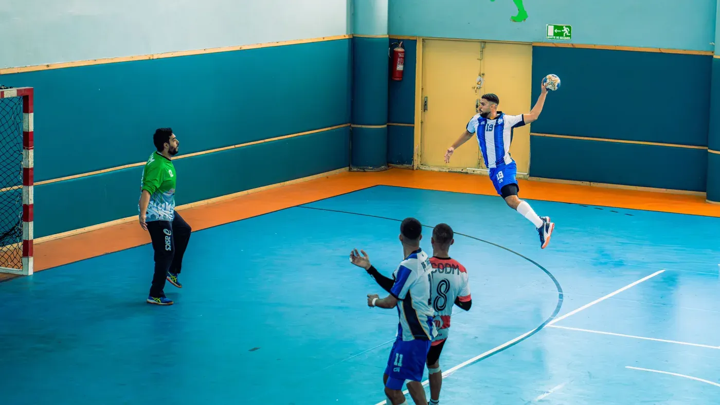 Handbollsspelare hoppar upp för skott mot mål i en idrottshall